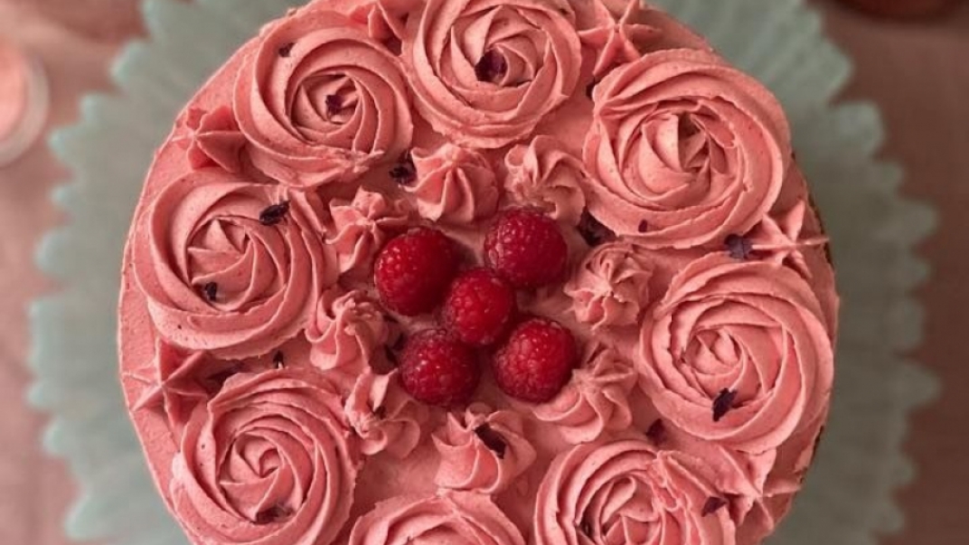top view of a cake with pinkish red icing and raspberries on top