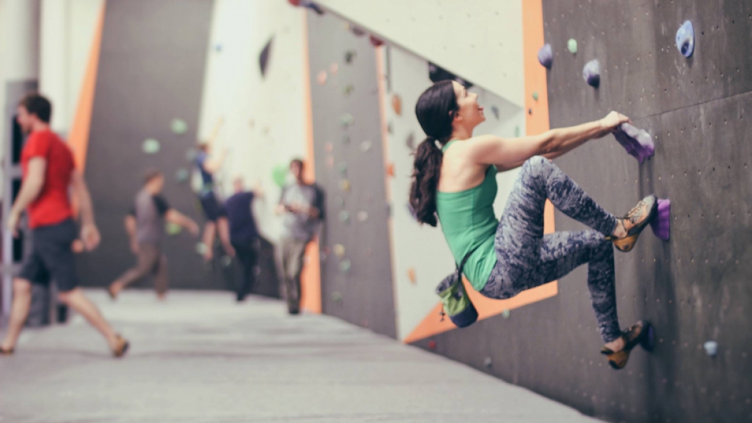 Woman in the foreground doing indoor bouldering