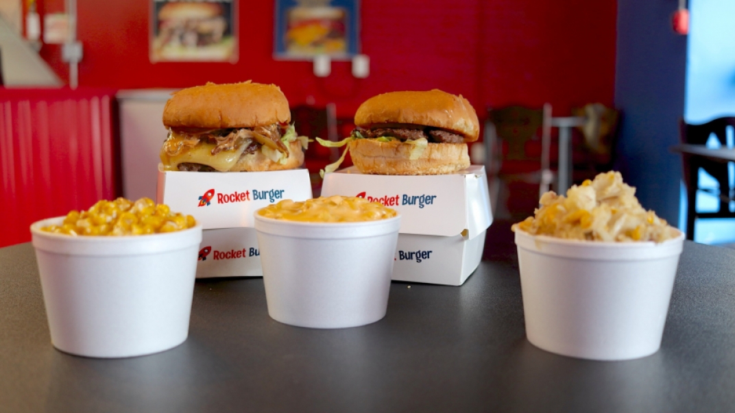 two cheese burgers with three sides in white styrofoam cups