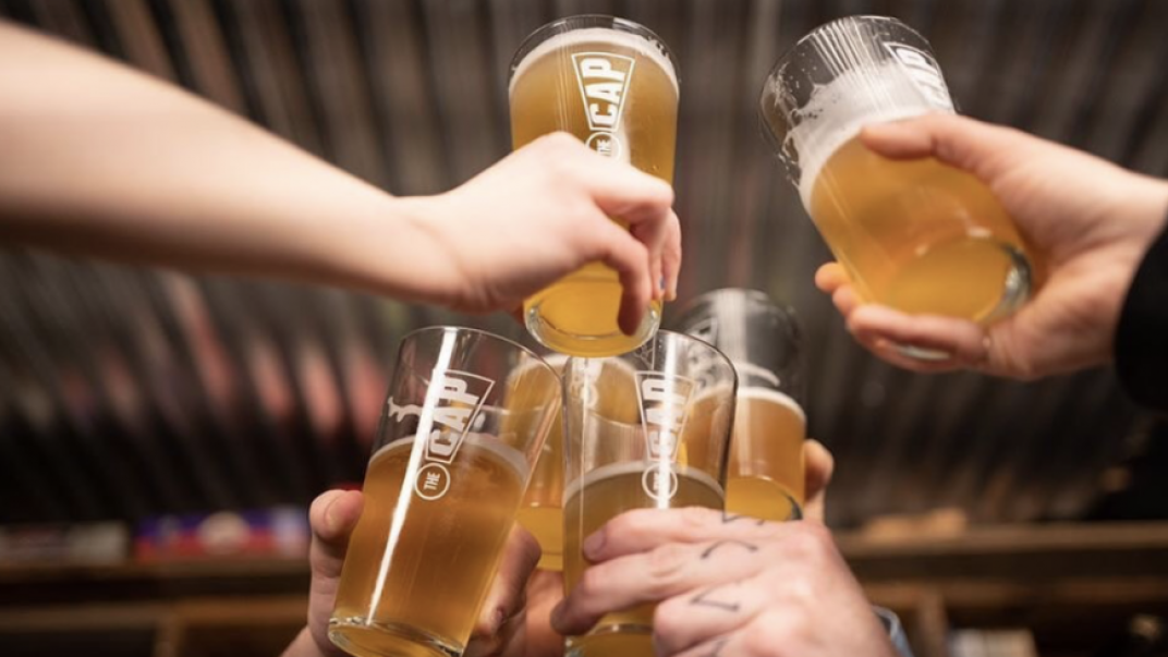 Group of hands holding beer pints