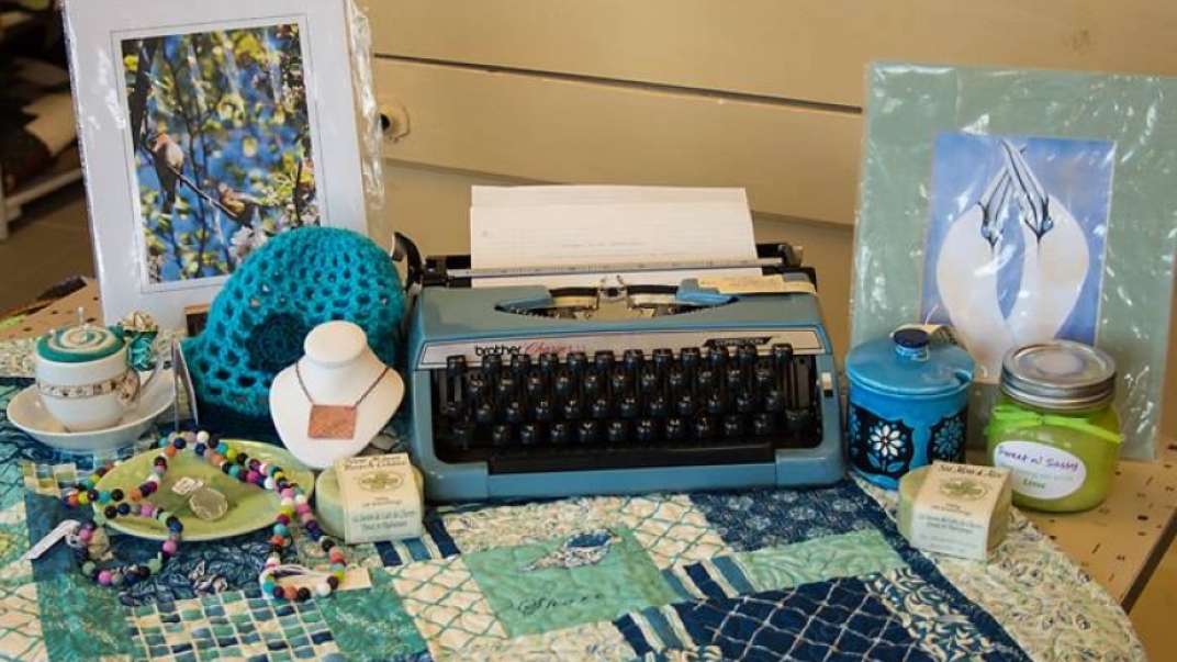 Table-spread with typewriter, handcrafted jewelry and paintings