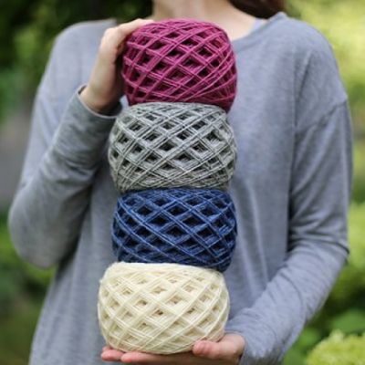 Woman holding four bundles of woolen yarn