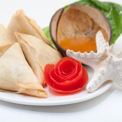 A plate with triangle pastries, a red flower, a white starfish, and half a coconut.