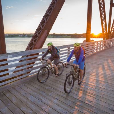 Two people riding bikes over bridge