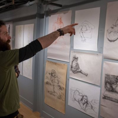 person pointing at sketches on a gallery wall