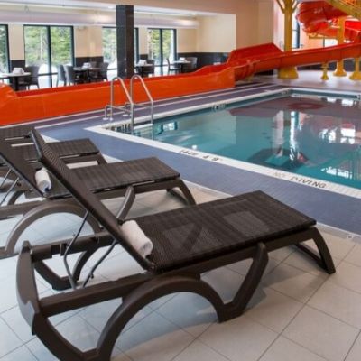 Image of an indoor pool with a red waterslide and lounge chairs on the pool deck
