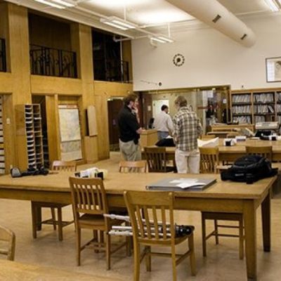 Archival library interior. There are some desks and chairs as well as bookcases filled with archival documents.