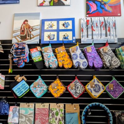 wall of wares including art, colourful patterned oven mitts and tea towels