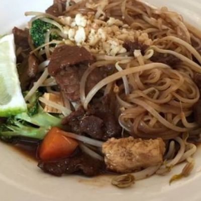 White bowl with noodles, beef and vegetables in it