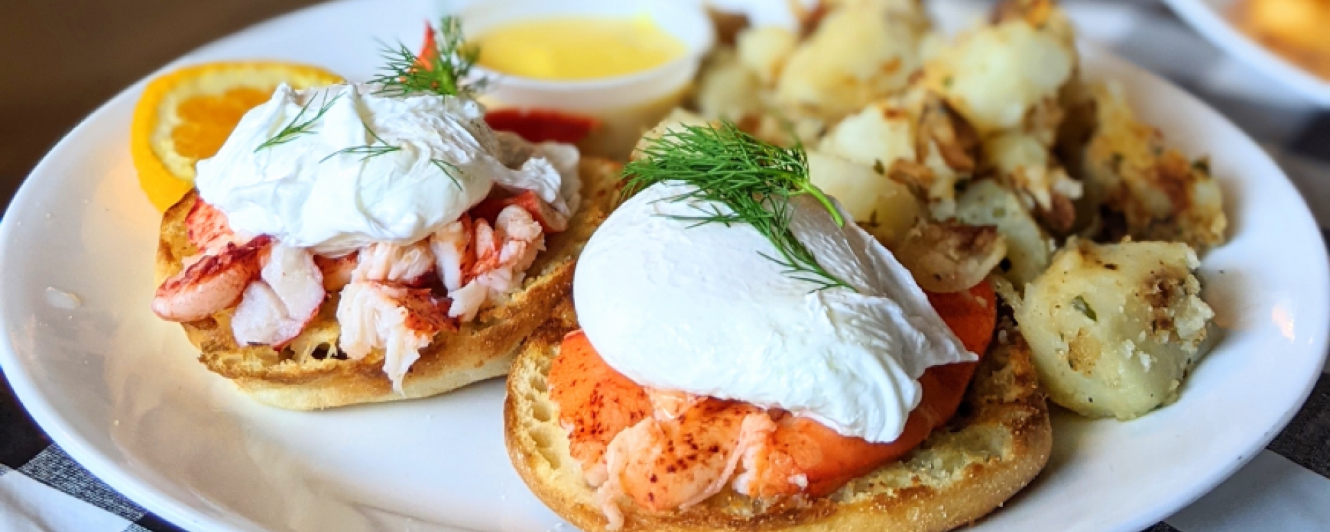 lobster Eggs Benedict with home fries on a white plate