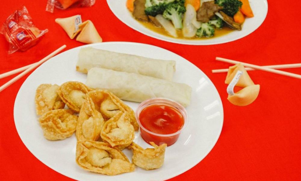 wantons and spring rolls with dip on a white plate and a red table cloth