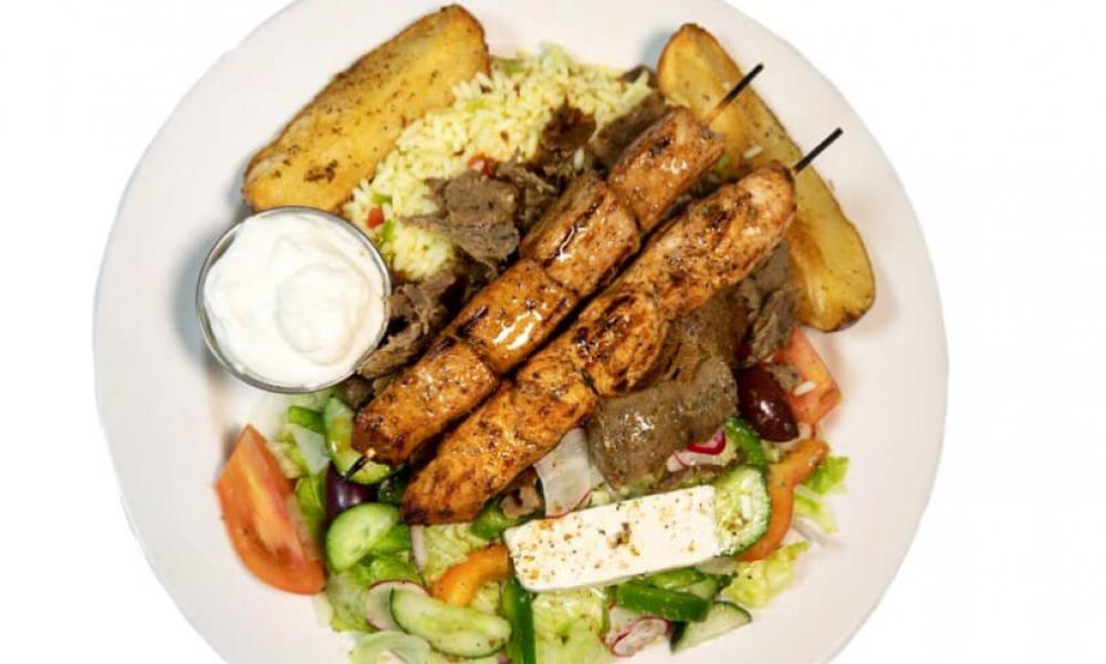 A souvlaki plate with kebabs, a salad, and rice. 