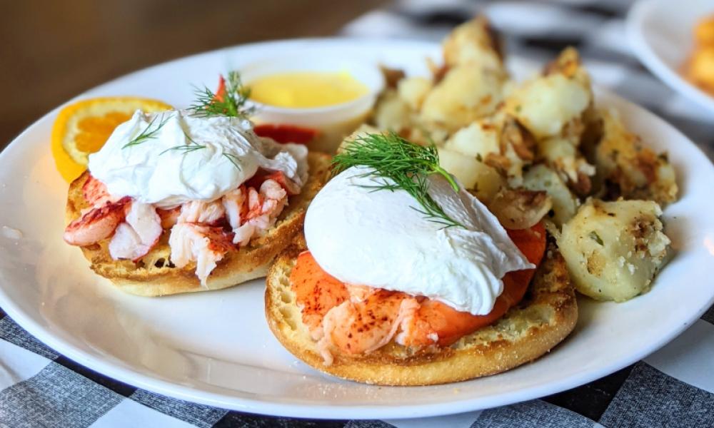 lobster Eggs Benedict with home fries on a white plate