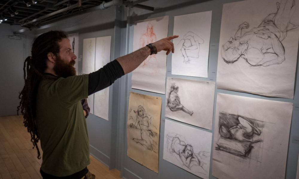 person pointing at sketches on a gallery wall