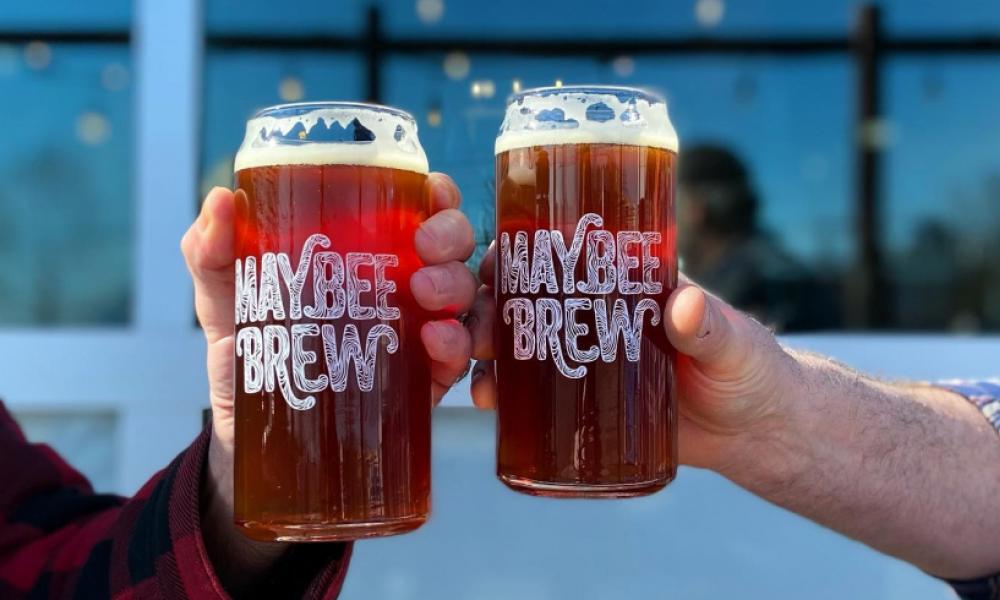 maybee brewery glasses fill with beer and two hands toasting
