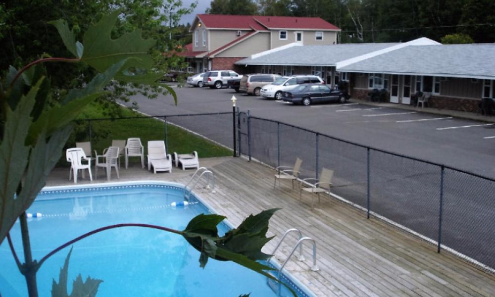 an fenced in outdoor pool and a hotel parking lot