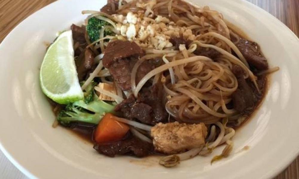 White bowl with noodles, beef and vegetables in it