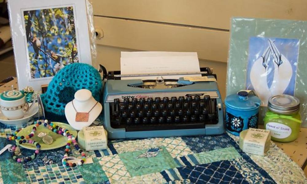 Table-spread with typewriter, handcrafted jewelry and paintings