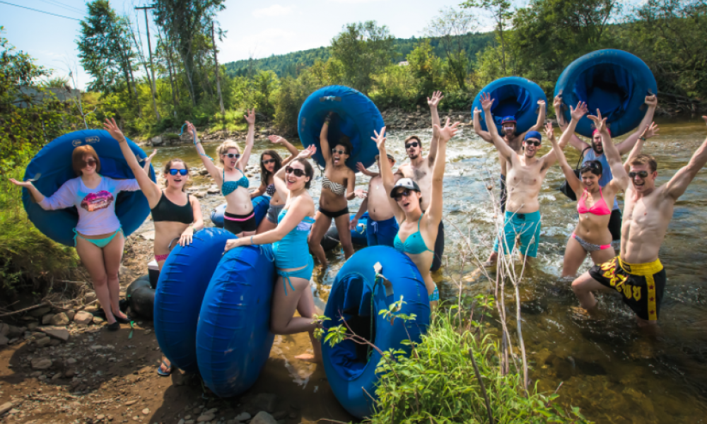 Group of people excitedly holding their tubing gear by the river